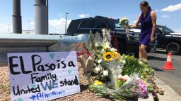 A woman places flowers at a growing memorial in El Paso.