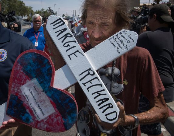 Antonio Basbo holds the cross of his common-law wife, Margie Reckard, who died in the shooting in El Paso.