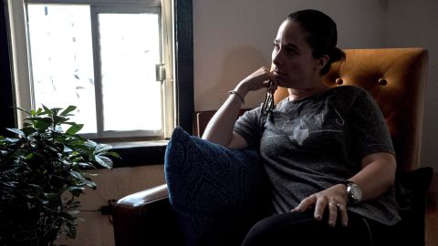 Adria Gonzalez, of El Paso, grips a rosary as she poses for a portrait inside her brother's home.