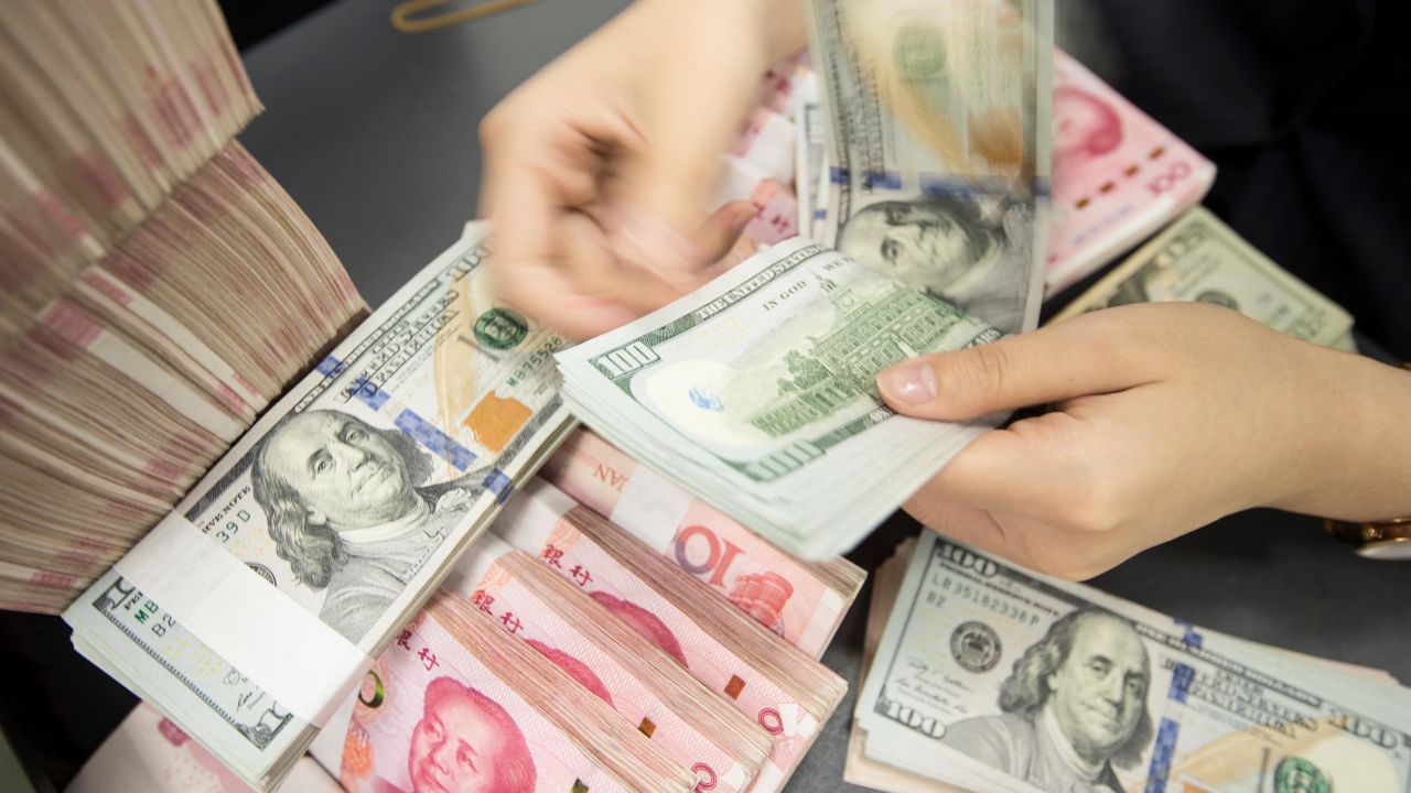 A Chinese bank employee counts 100-yuan notes and US dollar bills at a bank counter in Nantong in China's eastern Jiangsu province on August 6, 2019. - The Chinese currency steadied on August 6, a day after Beijing let the yuan weaken against the dollar, sending markets into freefall and leading the US to formally designate China a "currency manipulator". (Photo by STR / AFP) / China OUT        (Photo credit should read STR/AFP/Getty Images)