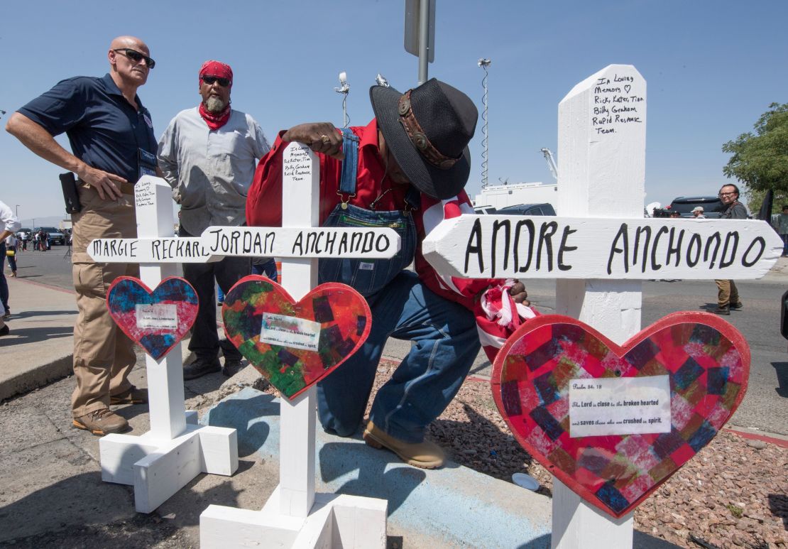 A man prays beside crosses bearing the names of Jordan and Andre Anchondo and the other victims of the El Paso massacre.