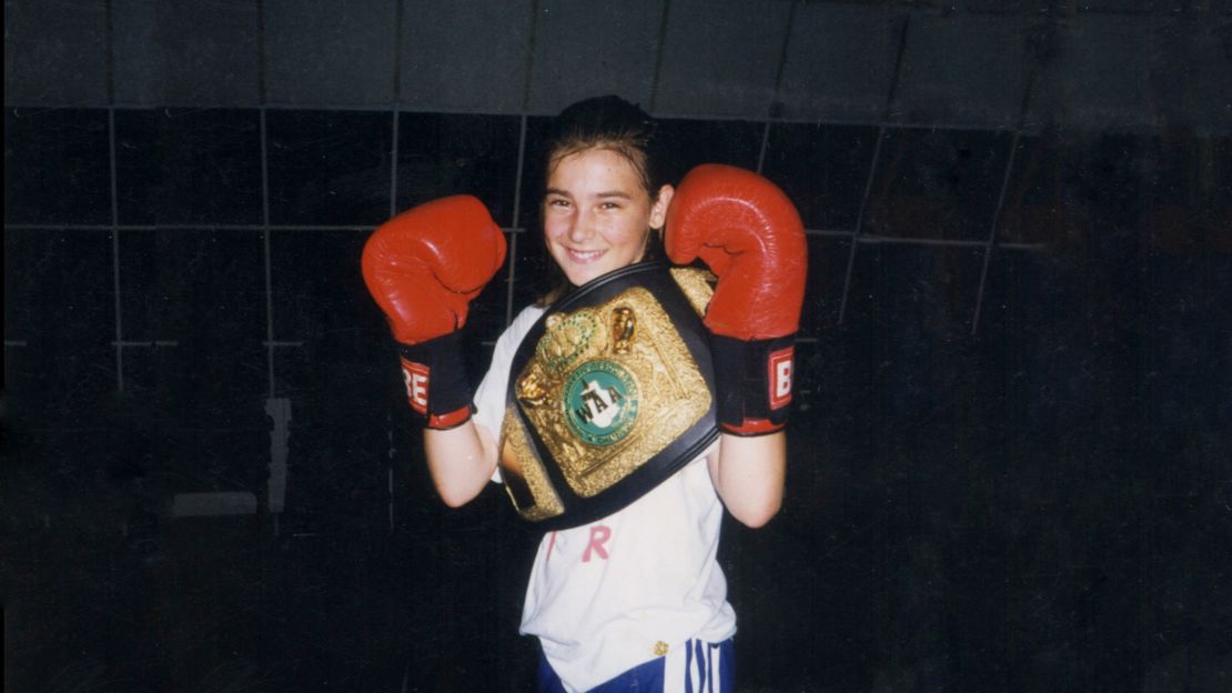 Katie Taylor with boxing gloves and a belt.