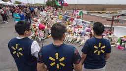 Walmart employees pay their respects at a makeshift memorial for the shooting victims, at the Cielo Vista Mall Walmart in El Paso, Texas, on August 6, 2019. - The August 3 shooting left 22 people dead. US President Donald Trump will visit the Texan border city August 7, and will also travel to Dayton, Ohio where a second mass shooting early August 4 left another nine dead. (Photo by Mark RALSTON / AFP)        (Photo credit should read MARK RALSTON/AFP/Getty Images)