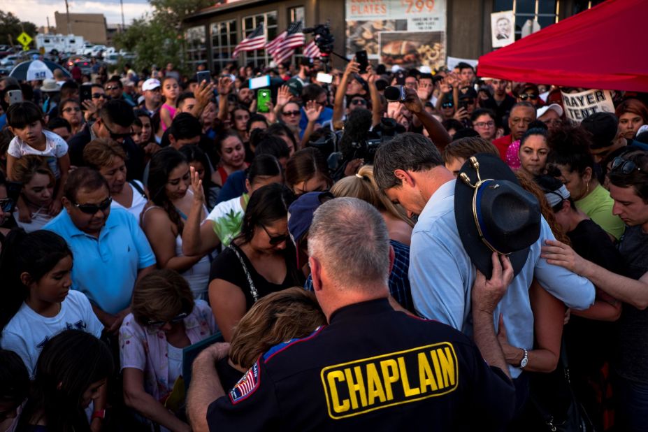 Democratic presidential candidate Beto O'Rourke, right, joins families in prayer during a visit to a makeshift memorial in El Paso. O'Rourke, a former congressman, is from El Paso.