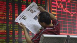 A man reads a newspaper at a brokerage in Beijing Wednesday, Aug. 7, 2019. Asian shares were mostly lower Wednesday as markets calmed after China's decision to stabilize its currency. (AP Photo/Ng Han Guan)