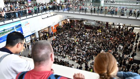 Tourists watch as protesters gather in the arrivals hall of Hong Kong international airport on July 26.