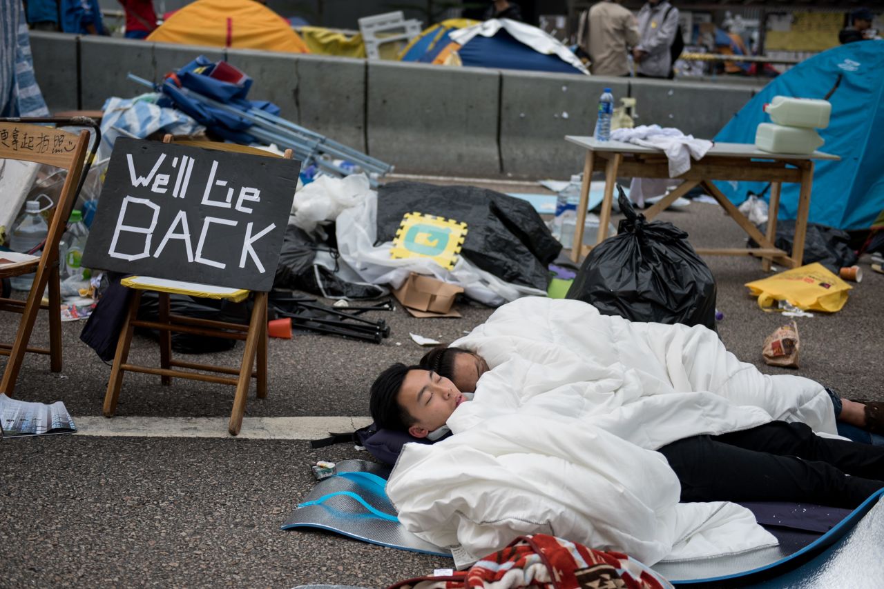 Pro-democracy protesters sleep next to a sign reading "we'll be back" on a blocked road in the Admiralty district of Hong Kong on December 11, 2014. 