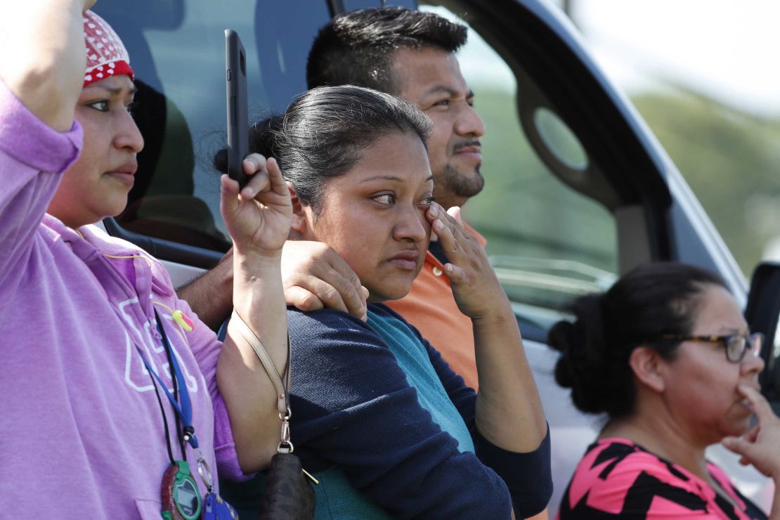 Friends, coworkers and family watch as U.S. immigration officials raid a plant in Morton, Mississippi.