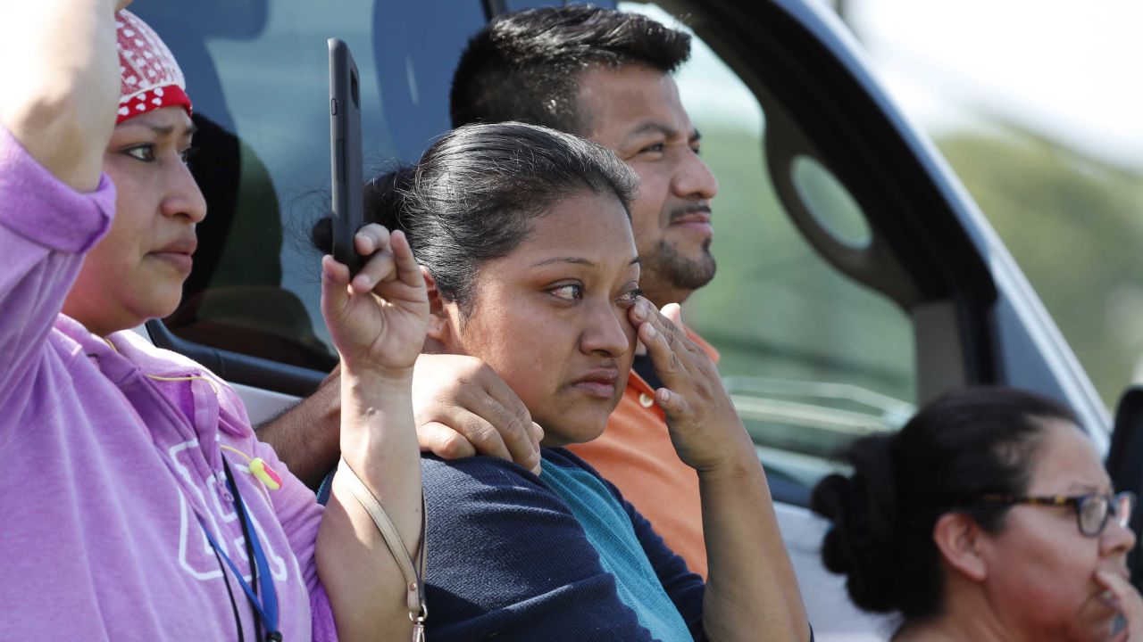 Friends, coworkers and family watch as U.S. immigration officials raid a plant in Morton, Mississippi.