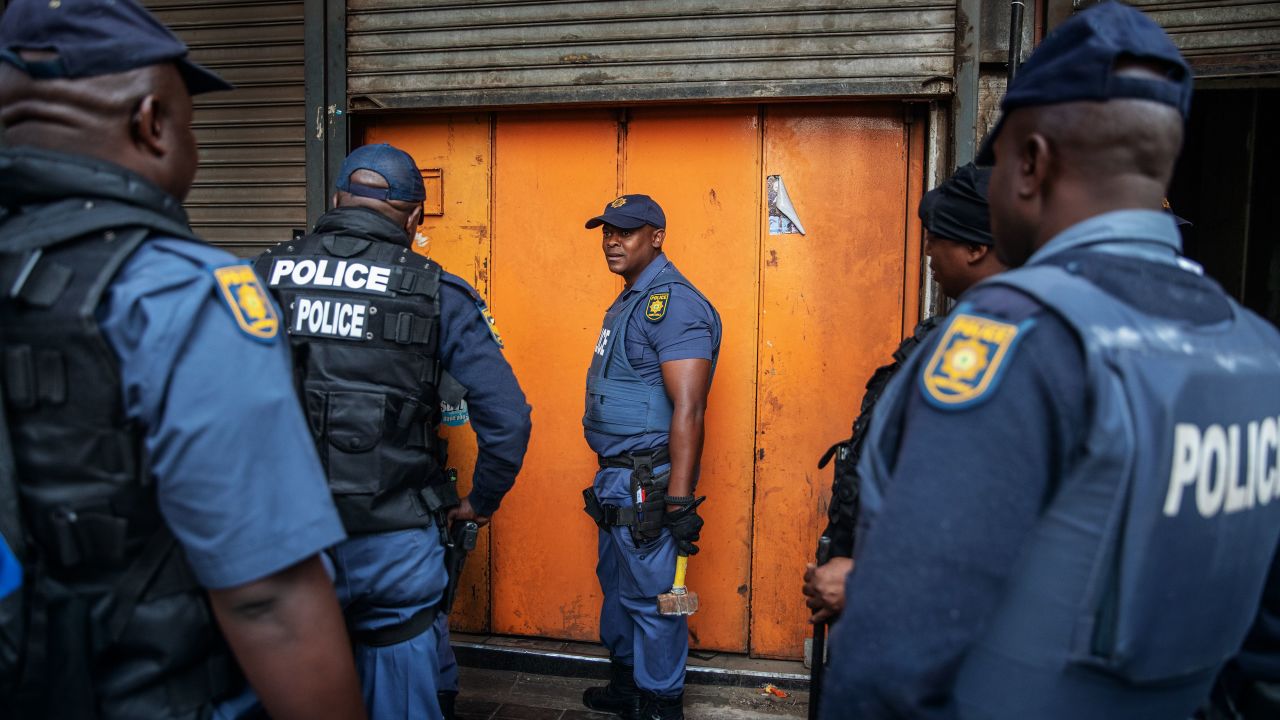 Police officers  in Johannesburg stand outside a locked shop allegedly containing counterfeit goods.