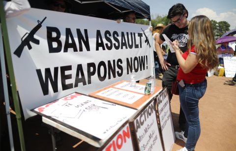 A "Ban Assault Weapons Now" sign is displayed near a voter registration table in El Paso.