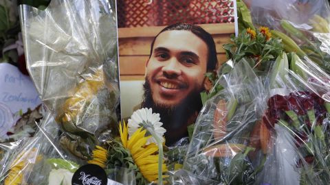 A photo tribute for Christchurch mosque shooting victim Tariq Omar lies amid mounds of flowers across the road from the Al Noor mosque in Christchurch, New Zealand Tuesday, March 19, 2019.