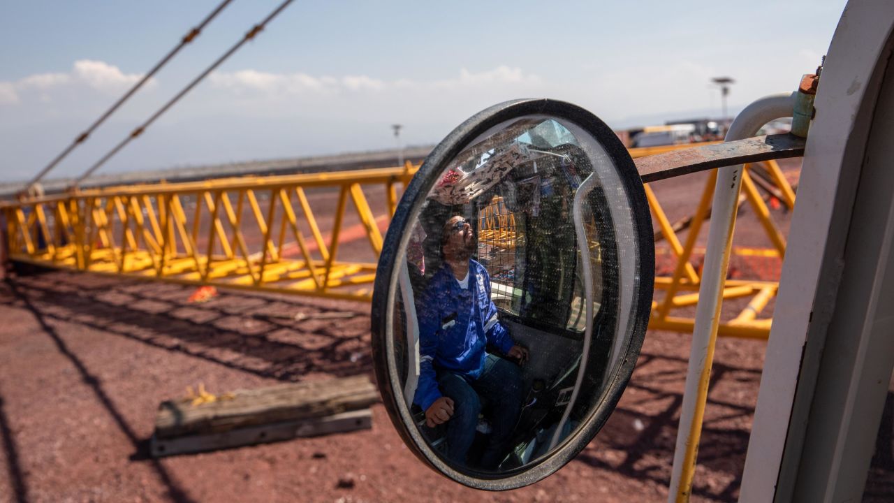 A worker is reflected in the mirror of a machine as cranes are removed from the New International Airport of Mexico City (NAICM) in Texcoco, Mexico.