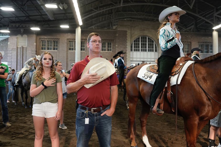 People hold their hands over their hearts as "God Bless America" is played before the Cowgirl Queen Contest.