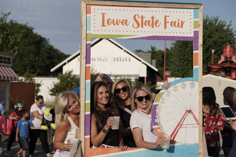 Women pose with their drinks at a photo booth.