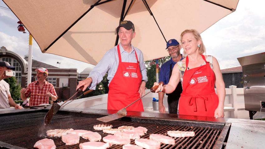 Democratic presidential candidates John Hickenlooper and Kirsten Gillibrand flip pork chops at the Iowa State Fair on Saturday.