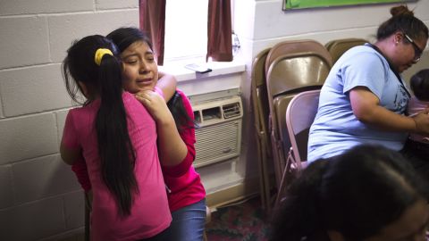 Edna Perez, 14, hugs one of her sisters inside the Trinity Mission Center in Forest, Mississippi. Their father was detained and is still in custody.