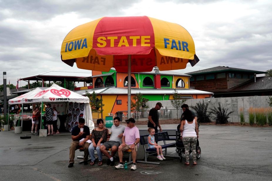 Fairgoers take shelter under an umbrella during a rainy Sunday.