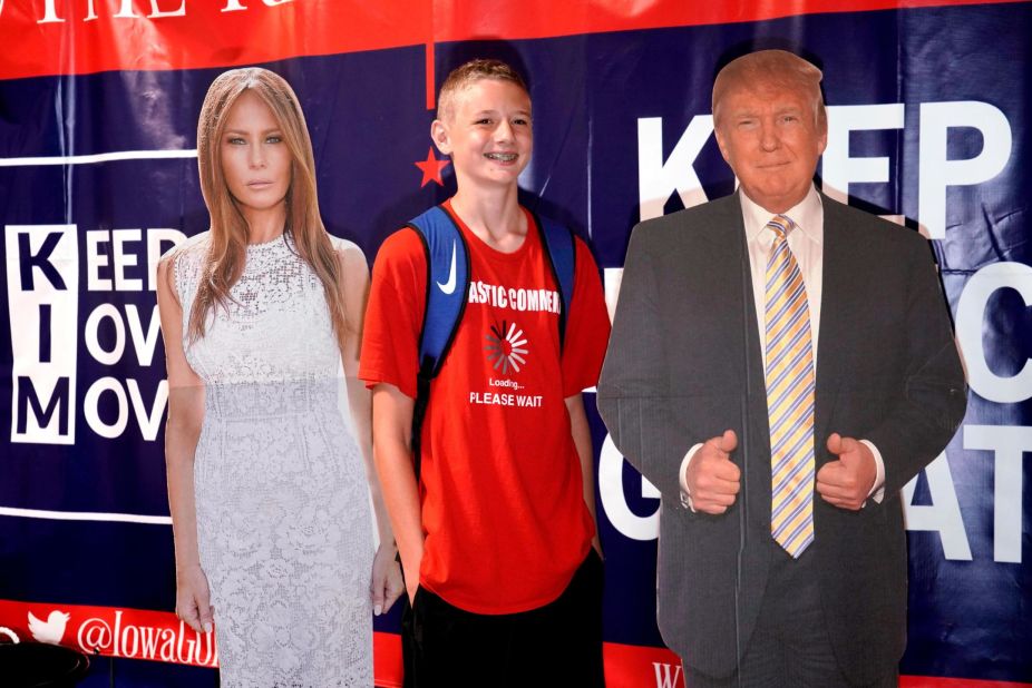 A young man poses with cutouts of President Trump and first lady Melania Trump.