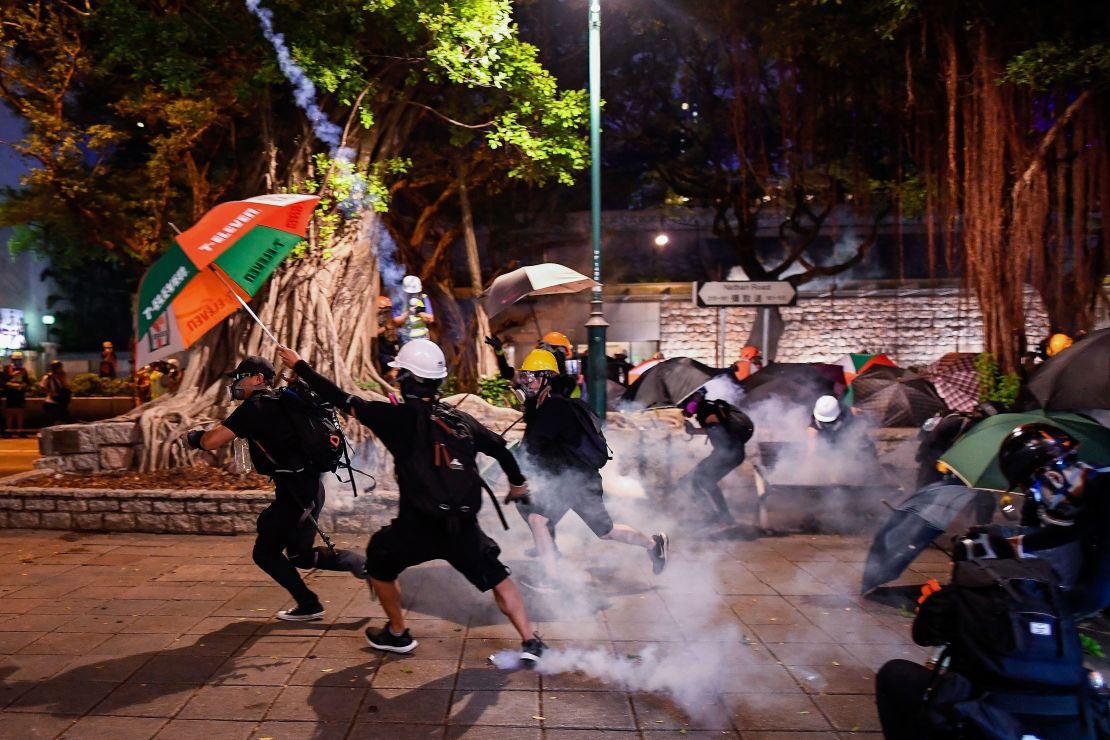 Pro-democracy protesters throw back tear gas cannisters in Tsim Sha Tsui district during a demonstration against the controversial extradition bill in Hong Kong on August 11, 2019.