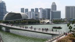 Visitors walk along the bridge leading to the Merlion park in Singapore.
