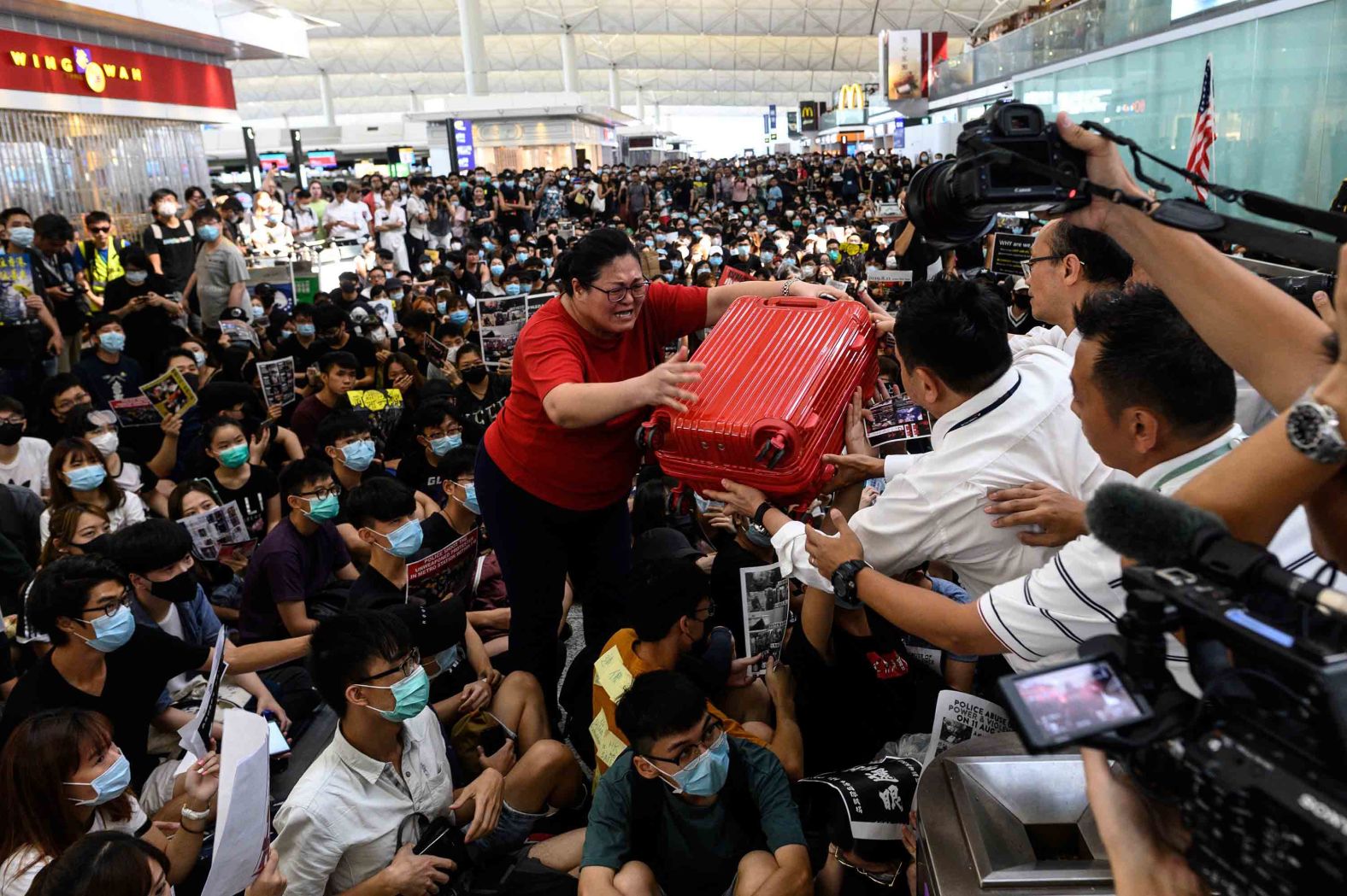 A traveler passes her luggage to security guards as she tries to enter the departures gate.