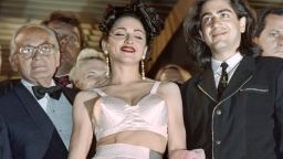 American pop star Madonna displays the outfit, designed by French Jean-Paul Gaultier, she is wearing under an ample coat as she leaves the Cannes Festival Palace after the screening of her movie "in Bed with Madonna", on May 13, 1991 in Cannes, while movie director Alex Keshinian (L) looks on. Madonna Louise Veronica Ciccone was the third of eight children born into a large Italian family in Michigan. Her father, Sylvio Ciccone, was a design engineer for General Motors, and her mother was Madonna Ciccone. AFP PHOTO GERARD JULIEN / AFP / GERARD JULIEN        (Photo credit should read GERARD JULIEN/AFP/Getty Images)