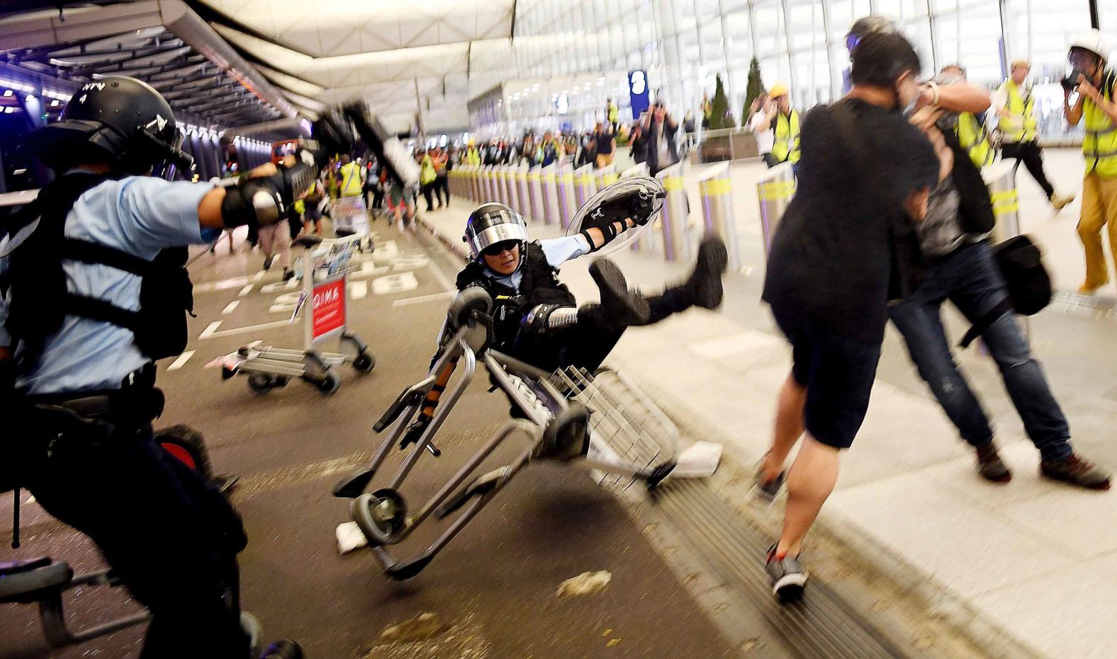 A police officer falls over an airport luggage trolley during a scuffle with pro-democracy protesters on Tuesday, August 13. For two days, <a href="https://www.cnn.com/2019/08/13/asia/hong-kong-airport-chaos-intl-hnk/index.html" target="_blank">protesters flooded the airport.</a> Check-ins were suspended and dozens of outgoing flights were canceled.