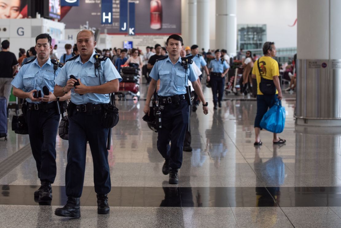 Police officers patrol in the departures hall of Hong Kong's International airport on August 14, 2019. 