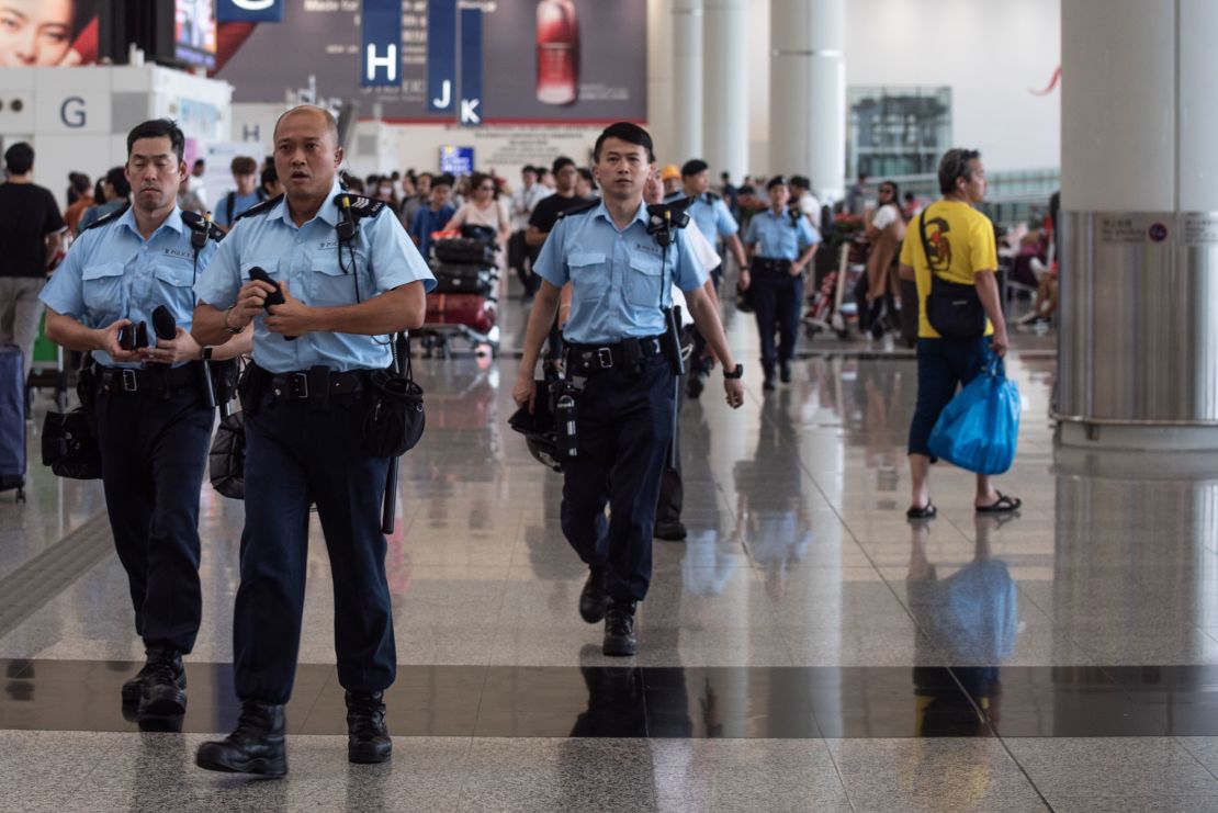 Police officers patrol in the departures hall of Hong Kong's International airport on August 14, 2019.