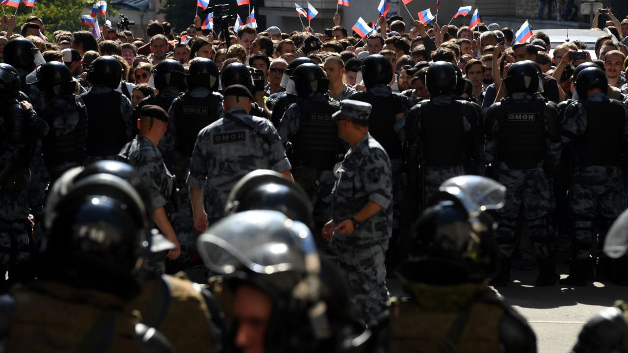 Protesters wave Russian flags as they confront riot police in Moscow.