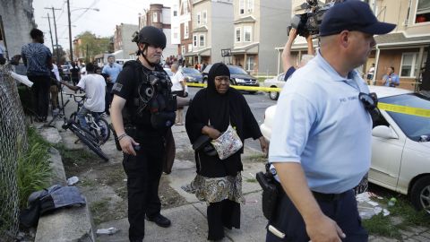 Police officers escort a bystander away from the scene of the shooting in Philadelphia on Wednesday. 