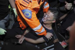 A medical staffer helps a detained man, who protesters claimed was a police officer from mainland China, during a demonstration at the Airport in Hong Kong, Tuesday, Aug. 13, 2019. Protesters severely crippled operations at Hong Kong's international airport for a second day Tuesday, forcing authorities to cancel all remaining flights out of the city after demonstrators took over the terminals as part of their push for democratic reforms. (AP Photo/Kin Cheung)