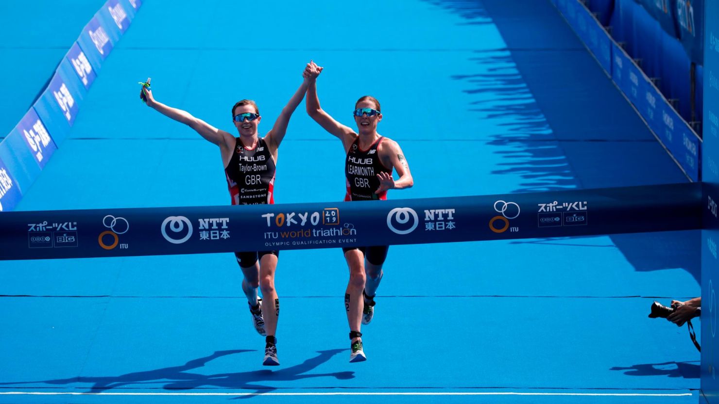 Britain's Georgia Taylor-Brown, left, and Jessica Learmonth hold hands as they cross the finish line.