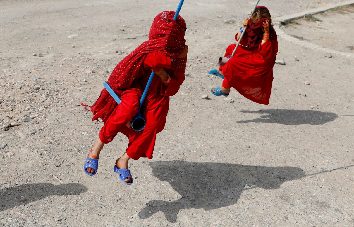 Girls cover their faces as they ride on swings in Kabul, Afghanistan, on Sunday, August 11. It was the first day of the Muslim holiday Eid al-Adha.