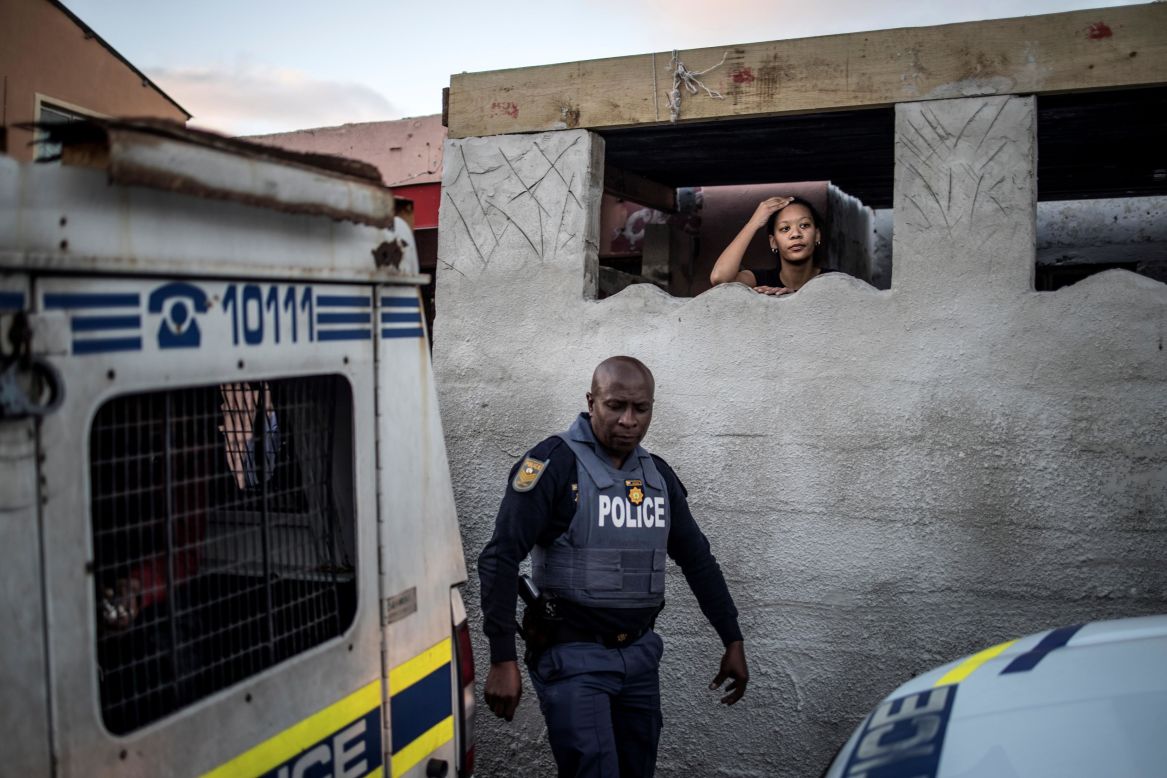 A relative of a detained man looks out as police leave their home in Cape Town, South Africa, on Friday, August 9. More than 1,000 South African service members have been deployed to Cape Town to support police in their efforts to prevent and combat crime.