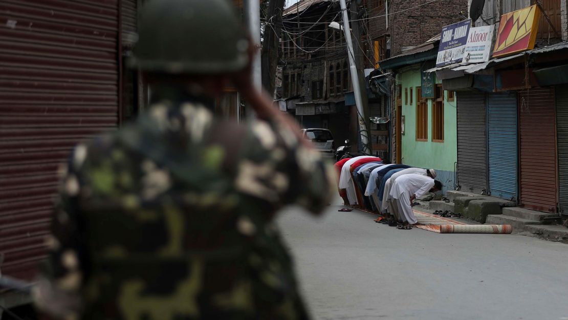 An Indian soldier stands guard as Kashmiri Muslims offer Friday prayers outside a Srinagar mosque on August 16.