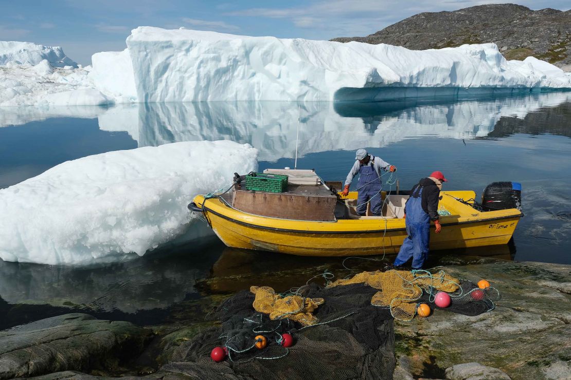 Inuit fishermen prepare a net as free-floating ice floats behind at the mouth of the Ilulissat Icefjord.