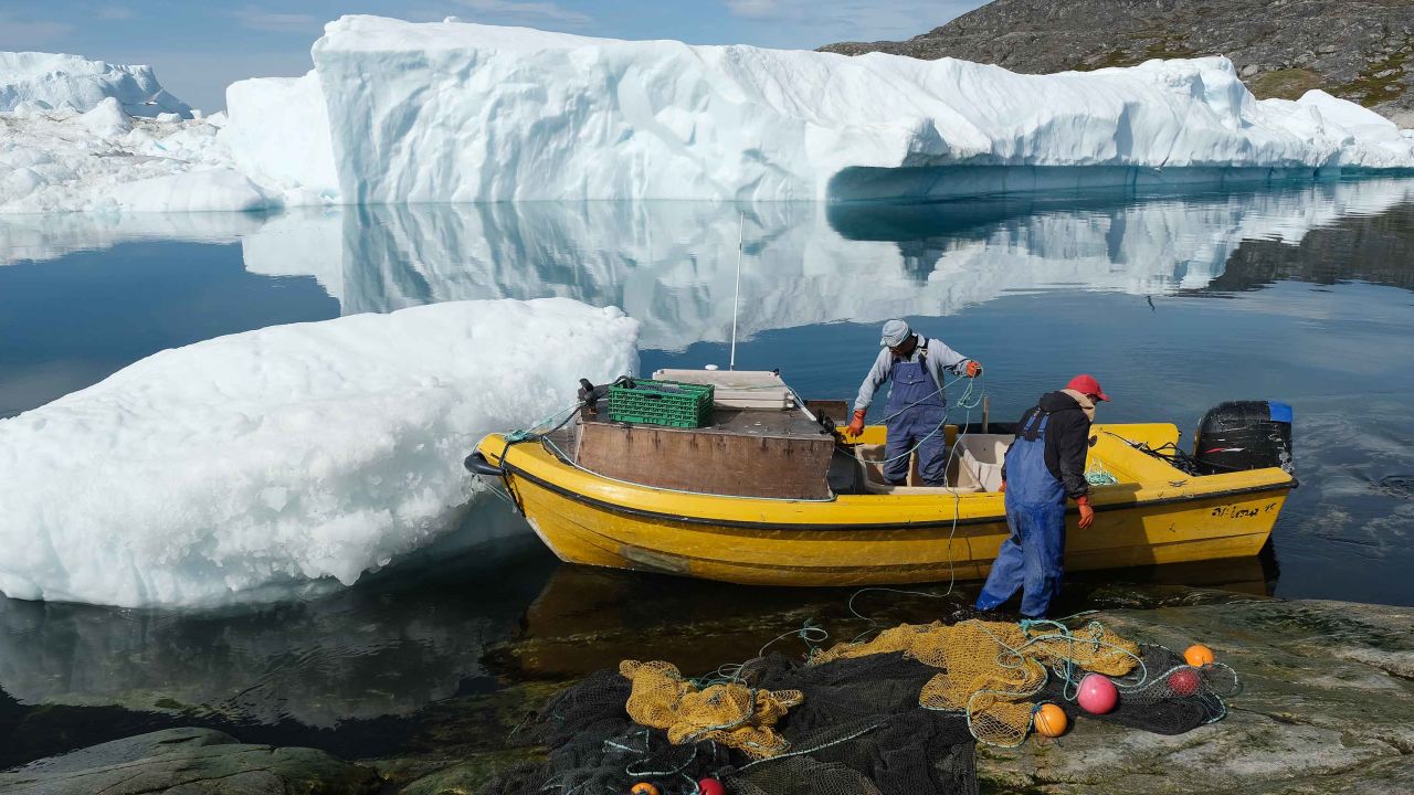 Inuit fishermen prepare a net as free-floating ice floats behind at the mouth of the Ilulissat Icefjord.