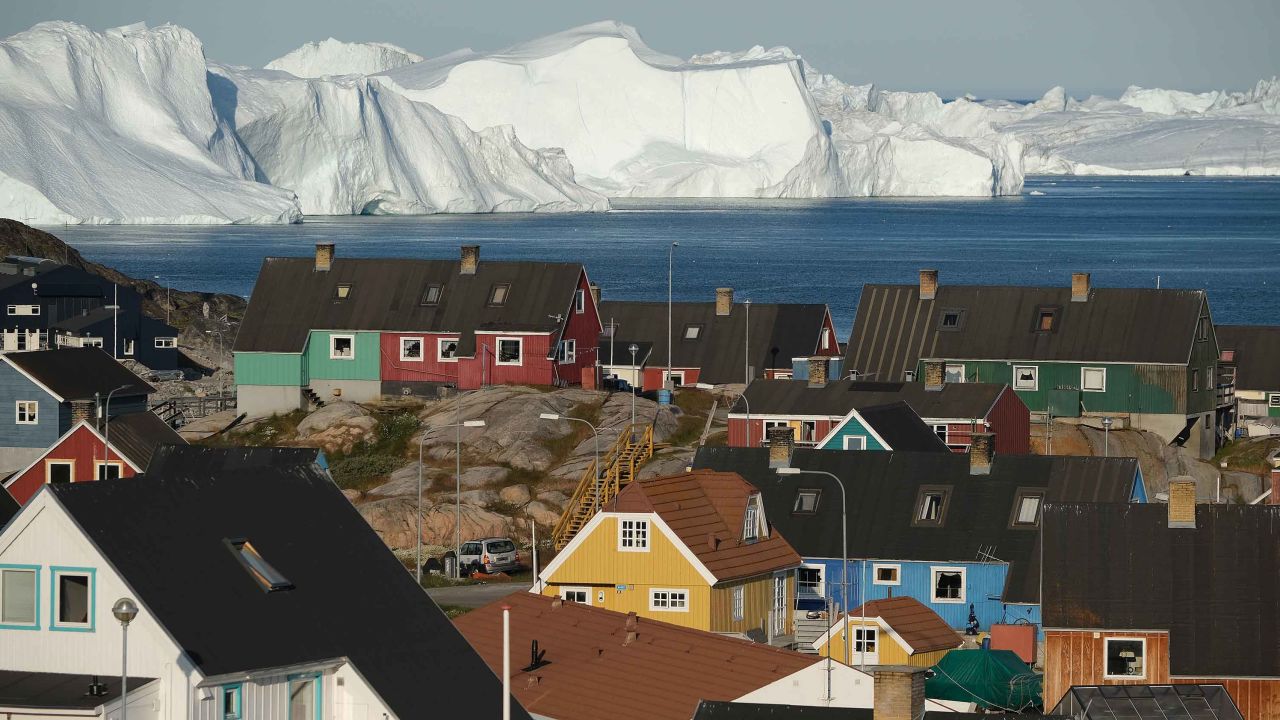 ILULISSAT, GREENLAND - JULY 30: Icebergs floating at the mouth of the Ilulissat Icefjord loom behind the town center on July 30, 2019 in Ilulissat, Greenland. As the Earth's climate warms summers have become longer in Ilulissat, allowing fishermen a wider period to fish from boats on open waters and extending the summer tourist season. Long term benefits are uncertain, however, as warming waters could have a negative impact on the local fish and whale population.  (Photo by Sean Gallup/Getty Images)