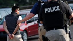 FILE - In this Aug. 7, 2019, file photo, a man is taken into custody at a Koch Foods Inc. plant in Morton, Miss. Unauthorized workers are jailed or deported, while the managers and business owners who profit from their labor often aren't. Under President Donald Trump, the numbers of owners and managers facing criminal charges for employing unauthorized workers have stayed almost the same. (AP Photo/Rogelio V. Solis, File)
