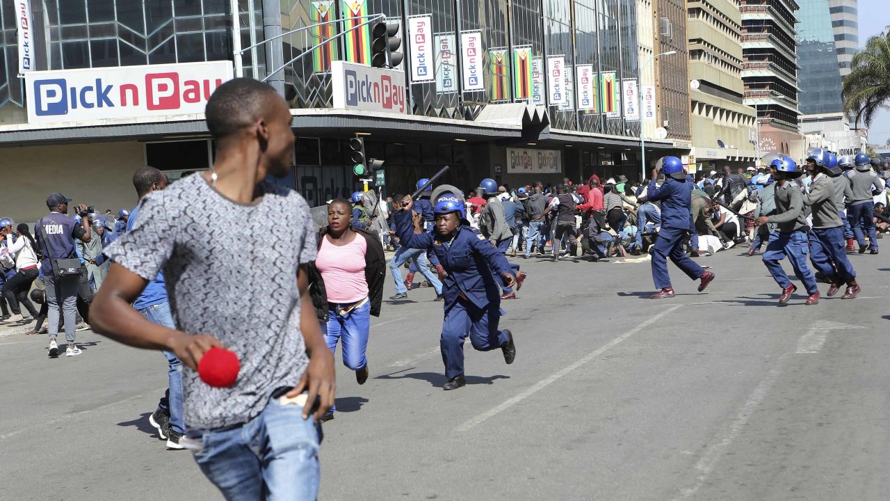 People run away from riot police armed with batons during clashes in Zimbabwe's capital on Friday.
