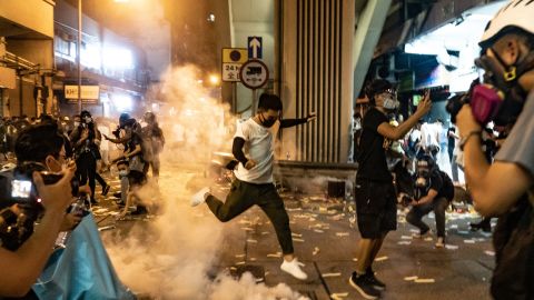 A protester attempts to kick a tear gas canister during a demonstration on Hungry Ghost Festival day in Sham Shui Po district on August 14, 2019 in Hong Kong.