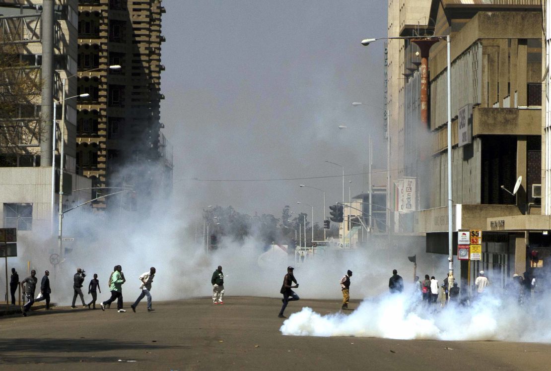 Protesters run from teargas fired by riot police during protests in Harare on Friday.