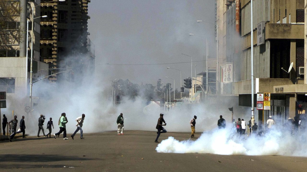 Protesters run from teargas fired by riot police during protests in Harare on Friday.