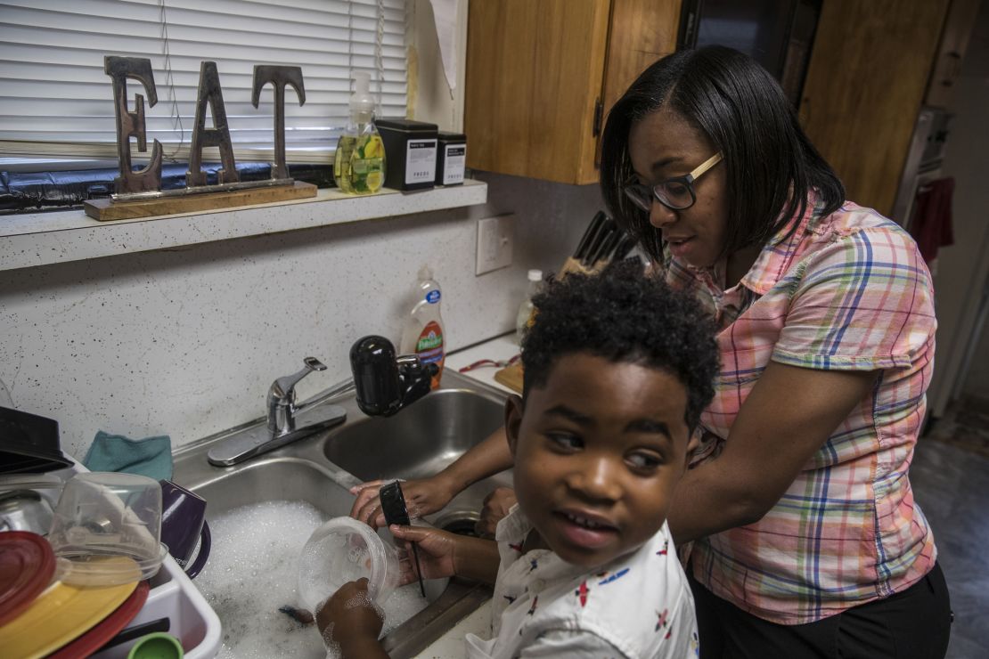 Shakima Thomas washes dishes with her 5-year-old son Bryce at their home in Newark. There are elevated levels of lead in the tap water.