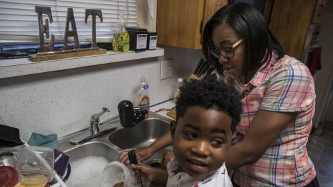 Shakima Thomas washes dishes with her 5-year-old son Bryce at their home in Newark. There are elevated levels of lead in the tap water.