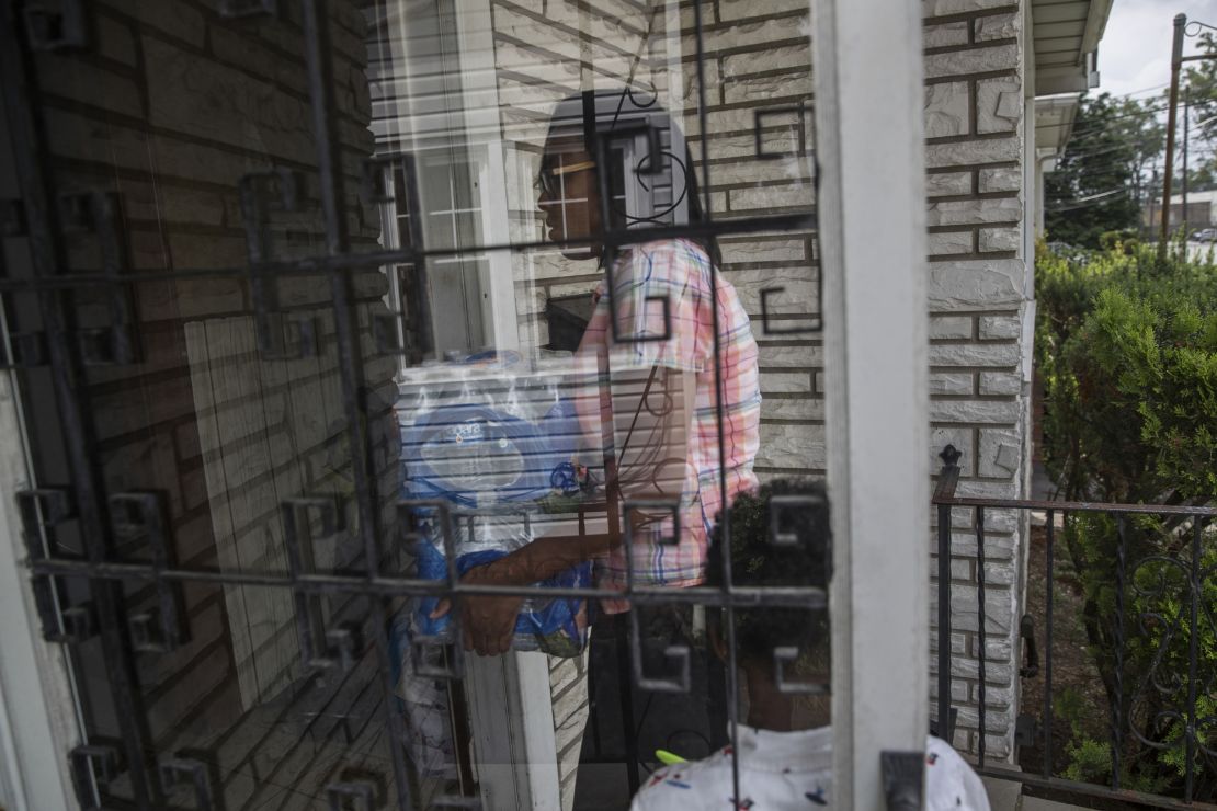 Shakima Thomas carries bottled water into her home.