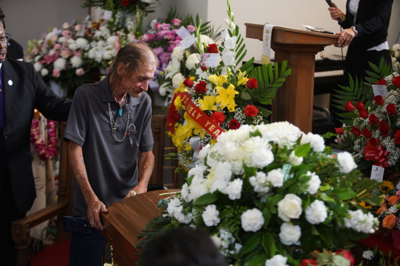 Basco leans on Reckard's casket during the funeral.