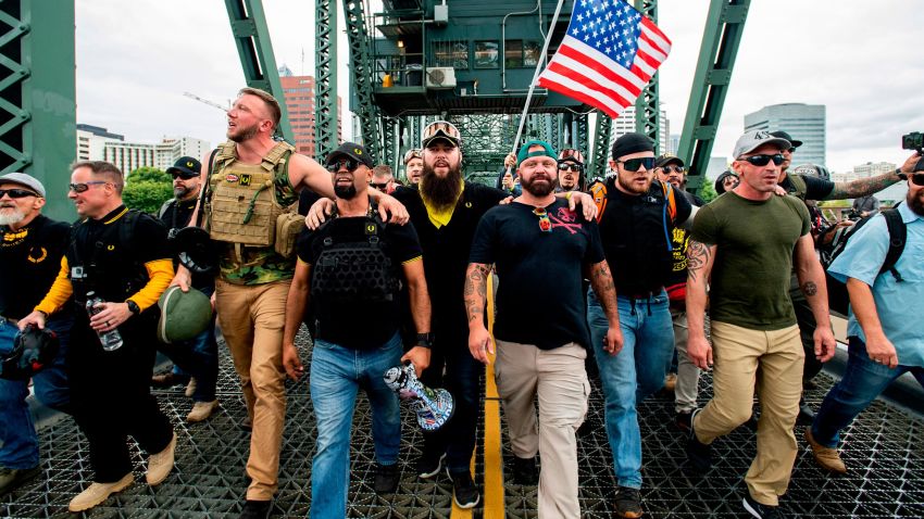 Members of the Proud Boys and other right-wing demonstrators march across the Hawthorne Bridge during an "End Domestic Terrorism" rally in Portland, Ore., on Saturday, Aug. 17, 2019. The group includes organizer Joe Biggs, in green hat, and Proud Boys Chairman Enrique Tarrio, holding megaphone. (AP Photo/Noah Berger)